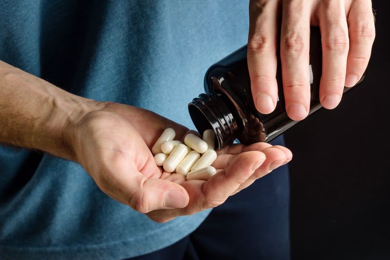 Person pouring white pills into their hand out of a brown glass bottle