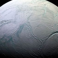 A quarter of enceladus is visible. the icy surface is marked by deep, long, and sinous canyons