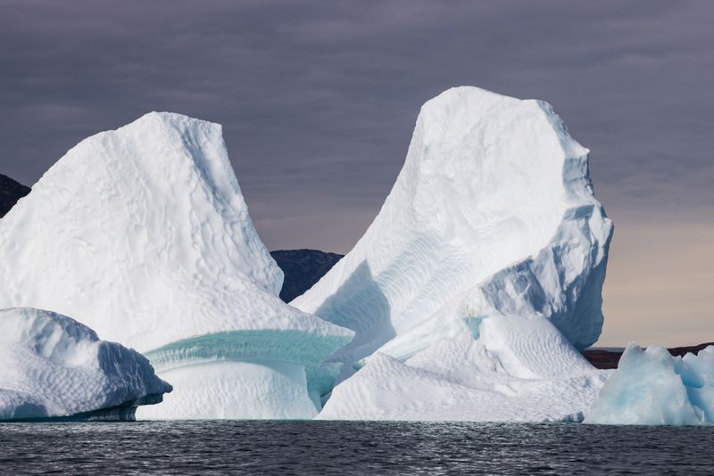 Iceberg floating in water. Kayaking in Tasiusaq ice fjord 