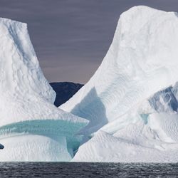 Iceberg floating in water. Kayaking in Tasiusaq ice fjord 