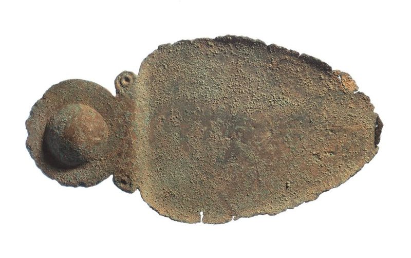 A photo of the spoon on a white background. The spoon shows off a characteristic strawberry shape. It has rough worn edges and two small spiral shapes are visible at the point where the handle meets the bowl. 