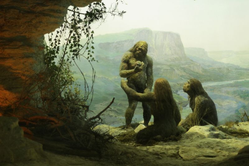 Neanderthals standing around in a mountain cave.