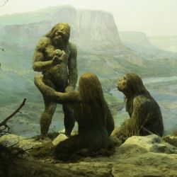 Neanderthals standing around in a mountain cave.
