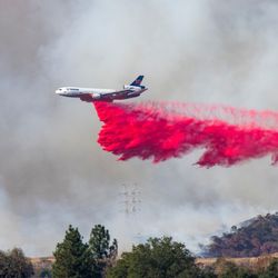 A plane flying across a smoky sky and dropping fire retardant on the Palisades Fire, January 11, 2025.