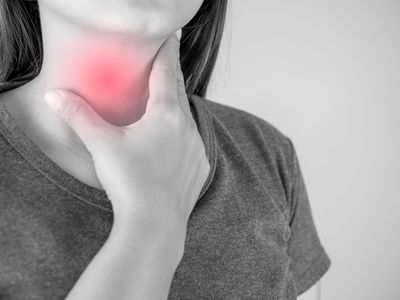 black and white close up of a woman holding her throat, with red overlay to indicate pain