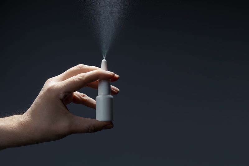 close up of a hand holding a nasal spray bottle