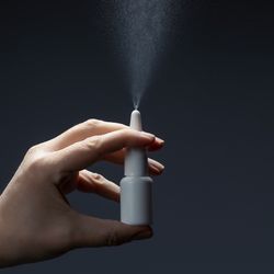 close up of a hand holding a nasal spray bottle