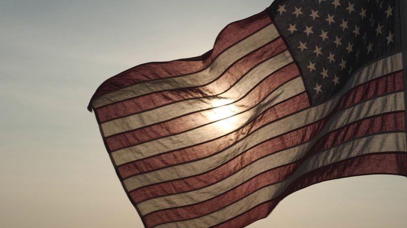 US flag flying towards the left with the sunset behind