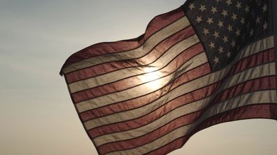 US flag flying towards the left with the sunset behind