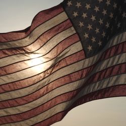 US flag flying towards the left with the sunset behind