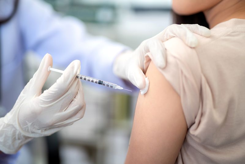 Close up of a healthcare professional injecting a vaccine into the shoulder of patient.