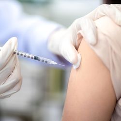 Close up of a healthcare professional injecting a vaccine into the shoulder of patient.