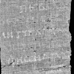 The photo shows a black and white image of a section of the scroll rendered in black and white. There are some Greek characters visible on the papyrus, which appear as a lighter tone against the grey backdrop. 