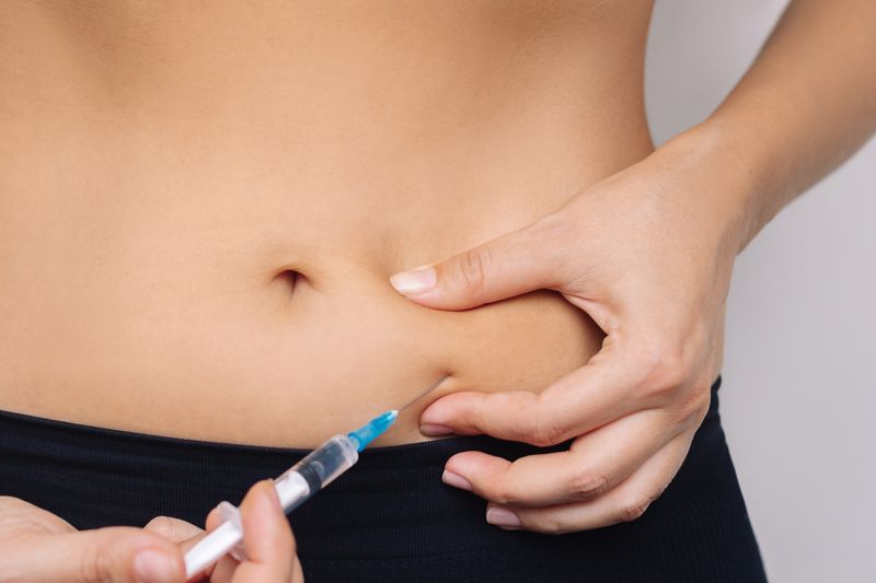 Woman injecting herself in the stomach with a needle