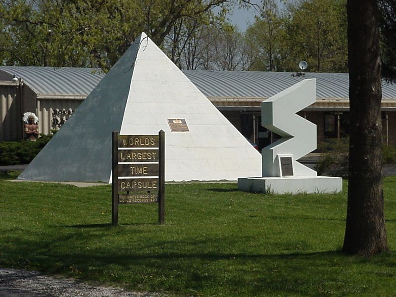 World's largest time capsule in Seward, Nebraska, a white pyramid with a brown sign in front of it and a smaller structure in the shape of a vertical zigzag