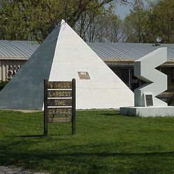 World's largest time capsule in Seward, Nebraska, a white pyramid with a brown sign in front of it and a smaller structure in the shape of a vertical zigzag