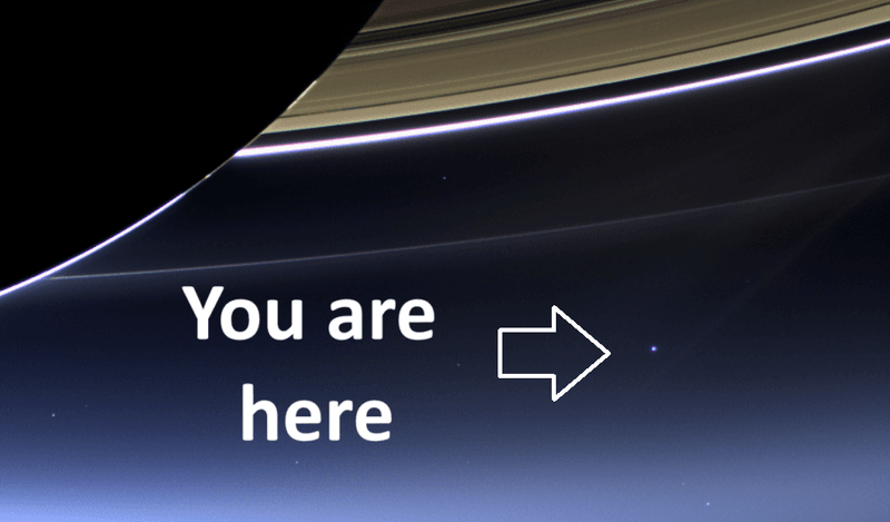 Giant arrow pointing to Earth,  seen as a blue dot underneath the rings of Saturn.  