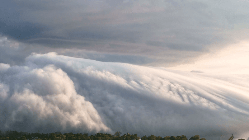 A pretty spectacular wave of fog rolls over in the sky. It looks like an ocean wave but is entirely white. 