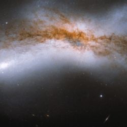 a large dark band of celestial dust is visible against the brigher fuzziness of a messy collision goin on behind