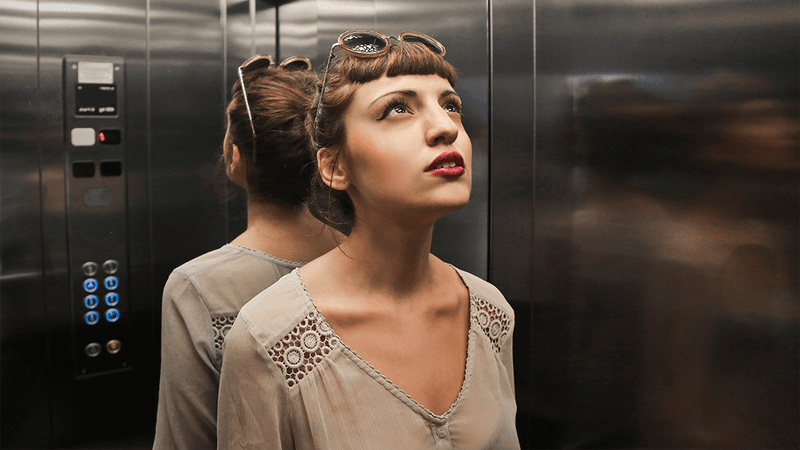 Mirrors in an elevator, plus passenger.