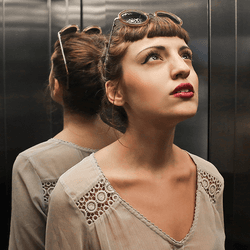 Mirrors in an elevator, plus passenger.