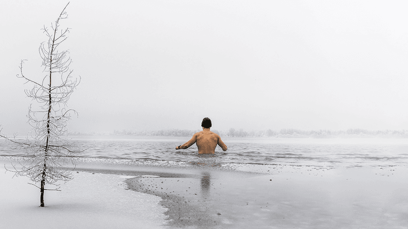 A man topless in a cold lake.