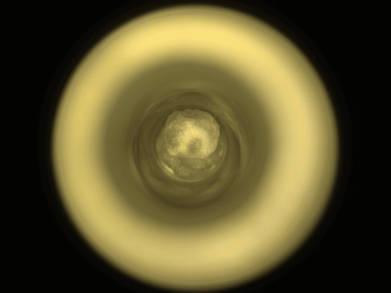 the camera is looking down a circular canister. at the end a silvery ragged pebble