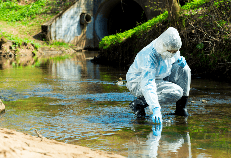 Scientists in hazmat suit takes water samples from a river, illustrating the environment contamination of PFAS