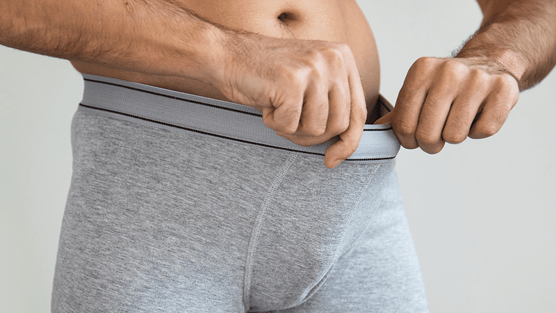 A man looking inside his underpants.