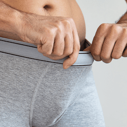 A man looking inside his underpants.