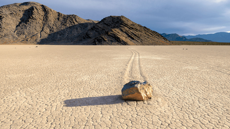 a rock sitting on racetrack playa, you can see a line carved in the lakebed where it has moved