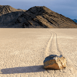 a rock sitting on racetrack playa, you can see a line carved in the lakebed where it has moved
